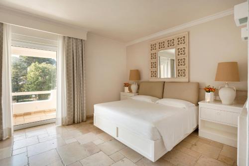 a white bedroom with a large bed and a window at Ostuni a Mare in Ostuni