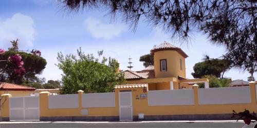 una casa amarilla con una cerca blanca delante de ella en Playa Eucaliptos 1A, en Isla Cristina