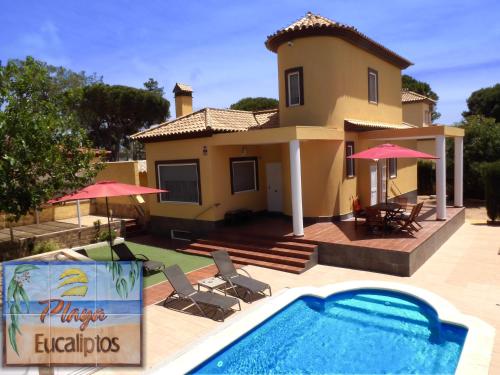 a villa with a swimming pool in front of a house at Playa Eucaliptos 1A in Isla Cristina