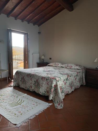 um quarto com uma cama com colcha floral e uma janela em Il Glicine em Bucine