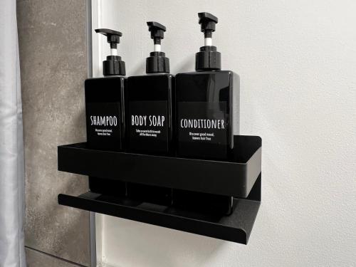 a black shelf with four bottles of soap on it at Luxury apartment - La fenice in Bari