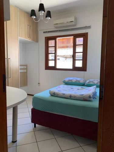 a bedroom with a bed and a window at Casa prox á praia e aeroporto in Florianópolis