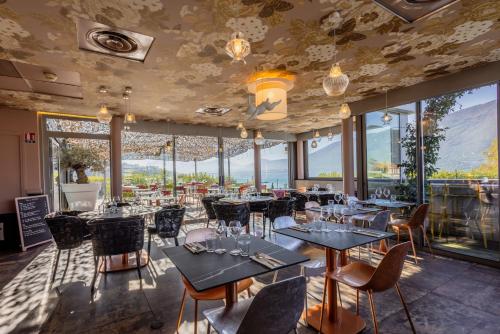 restauracja ze stołami i krzesłami oraz dużymi oknami w obiekcie Best Western Aquakub w Aix-les-Bains