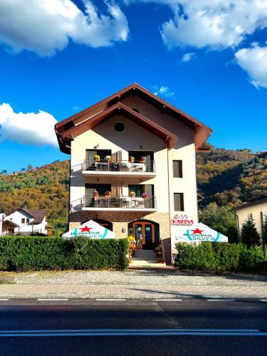 a building with a balcony on the side of a street at Pensiunea Karina in Caciulata