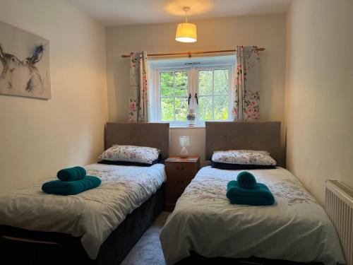 - 2 lits dans une chambre avec des oreillers verts dans l'établissement Forestry Cottage. Hot tub, open fire, dog friendly, à Gaywood