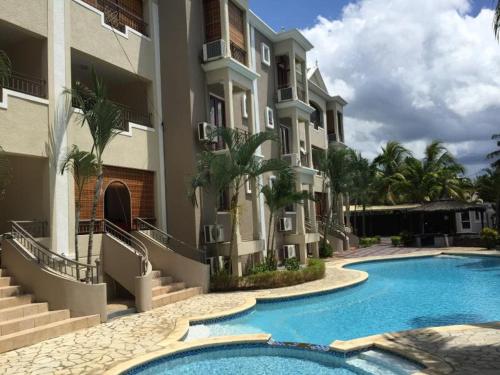 a building with a swimming pool in front of a building at MAURISIA APARTMENT Trou Aux Biches in Pamplemousses Village