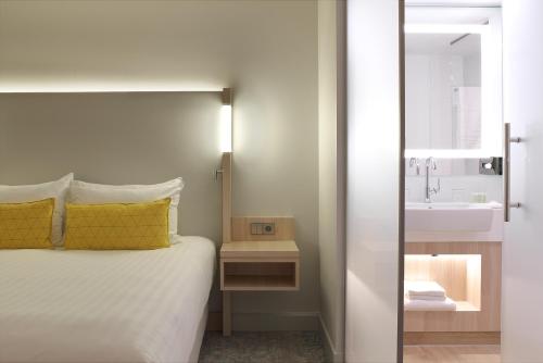 een slaapkamer met een bed en een wastafel bij The Jangle Hotel - Paris - Charles de Gaulle - Airport in Le Mesnil-Amelot