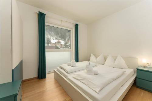 ein weißes Bett in einem Zimmer mit Fenster in der Unterkunft Appartement Göbel by Schladming Appartements in Haus im Ennstal