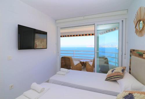 um quarto com uma cama, uma televisão e uma varanda em Magnificent and Luxury apartment at 22 floor and on the first line at Levante Beach beach em Benidorm
