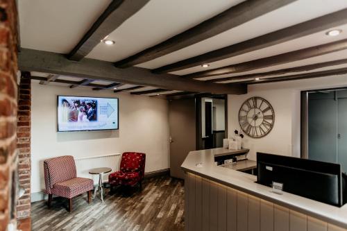 a lobby with a bar and chairs and a clock at Oak Farm Hotel in Cannock