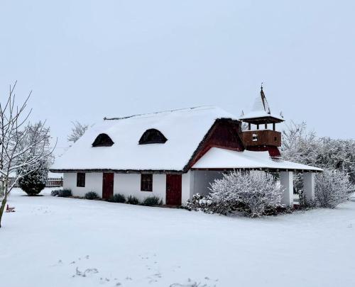 a white and red barn covered in snow at Enjoy the quiet nature in our unique cottage 