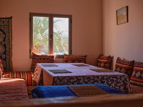 um quarto com uma mesa e cadeiras e uma janela em Panorama chez Hamid em Rissani