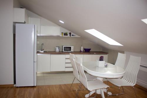 Una cocina blanca con una mesa y sillas blancas. en Apartman Mazić Nikšić, en Nikšić