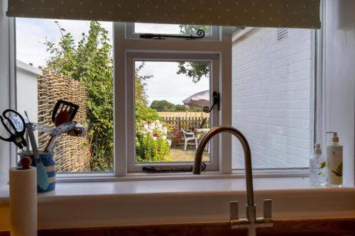 a kitchen sink with a window overlooking a garden at 4 Church Cottages in Reydon