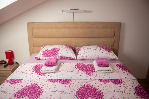 a bed with pink and white sheets and pillows at Apartman Mazić Nikšić in Nikšić