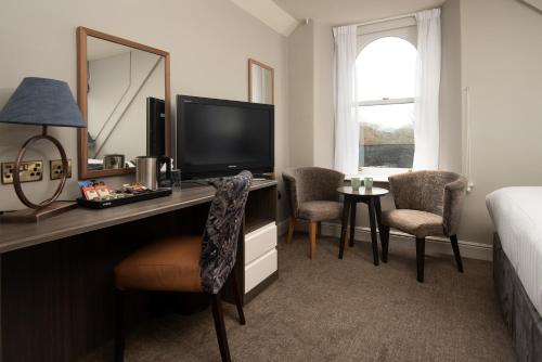 Windermere Rooms at The Wateredge Inn في آمبيلسايد: غرفة في الفندق مع مكتب مع تلفزيون وسرير