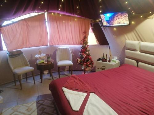 a bedroom with a christmas tree and a bed and chairs at Bubble castle house in Kerak