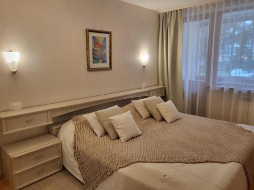 um quarto com uma cama com almofadas e uma janela em Apartamentai Taikos 10-36 Nida em Nida