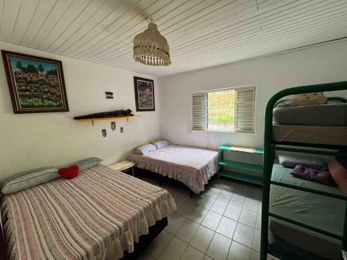 1 Schlafzimmer mit 2 Betten in einem Zimmer mit Fenster in der Unterkunft Chácara à beira do lago em São Luiz do Paraítinga in Natividade da Serra