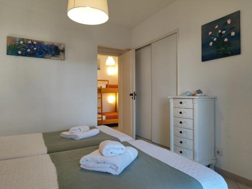 a bedroom with two beds and a dresser with towels at Albufeira Balaia Golf Vilage 4 With Pool by Homing in Albufeira
