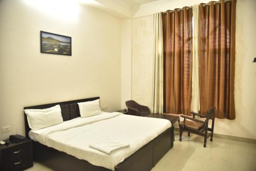 a bedroom with a bed and a chair and a window at IIDM Eco Centre in Lucknow