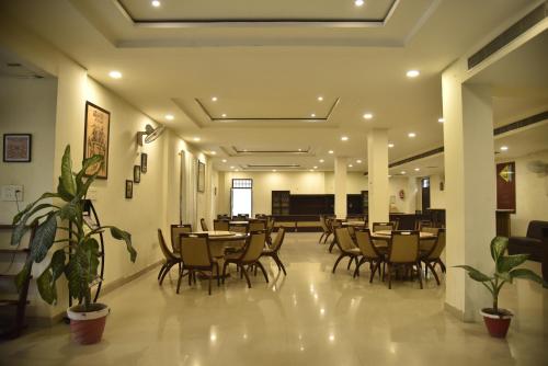 a dining room with tables and chairs and plants at IIDM Eco Centre in Lucknow