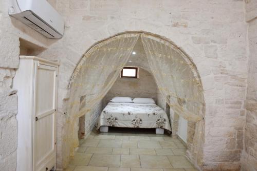 a bedroom with a bed in a stone wall at Agape fra i Trulli Dimora Orchidea in Alberobello