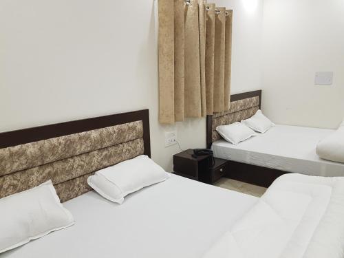 two beds in a room with white walls at New Gokul Grand in Dehradun