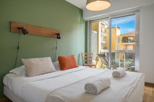 une chambre avec un grand lit blanc avec des serviettes dessus dans l'établissement Le Méditerranée - Charmant 3 pièces au coeur du centre ville de Menton, à Menton