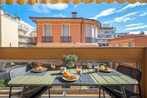 une table avec des assiettes de nourriture sur un balcon dans l'établissement Le Méditerranée - Charmant 3 pièces au coeur du centre ville de Menton, à Menton