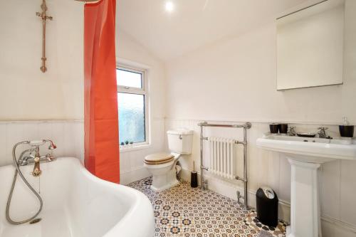 a bathroom with a tub and a toilet and a sink at Boutique London Abode - Games Room - Parking in Plumstead