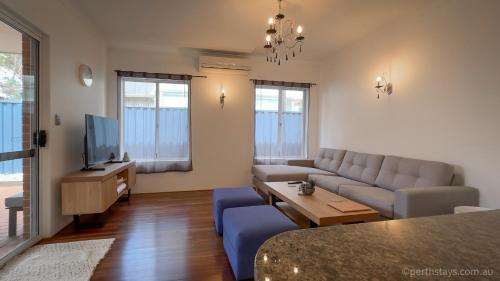 a living room with a couch and a tv at Fremantle High Street Retreat in Fremantle