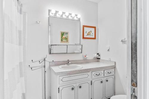 Baño blanco con lavabo y espejo en Cozy cottage for longer stays!, en Vero Beach