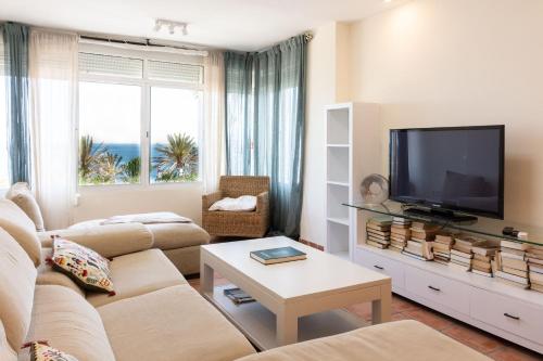 uma sala de estar com um sofá e uma televisão em Comodidad en primera linea de playa em Benalmádena