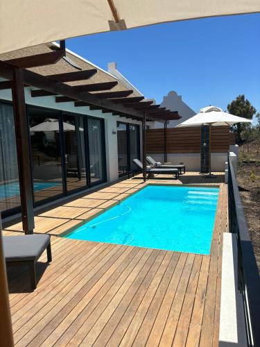 a swimming pool on a wooden deck with an umbrella at Vergenoegd Löw Boutique Hotel & Spa in Cape Town