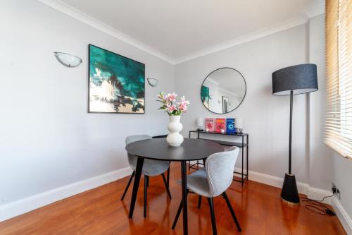 a dining room with a table and chairs and a vase with flowers at Cosy Apartment Steps From London Eye in London
