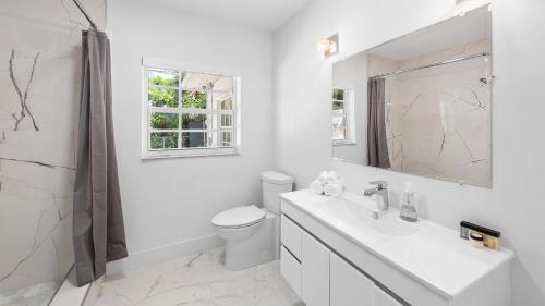 a white bathroom with a toilet and a sink at Villa Seabreeze in Fort Lauderdale