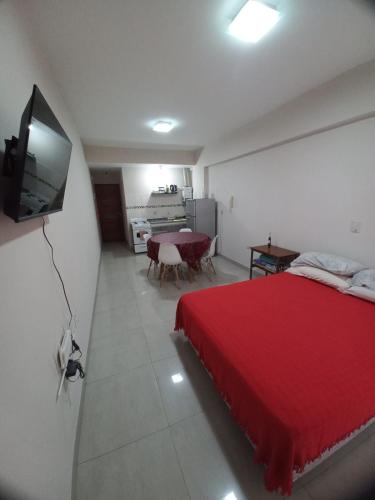 a bedroom with a red bed and a flat screen tv at Monoambiente Confortable Tucuman in San Miguel de Tucumán