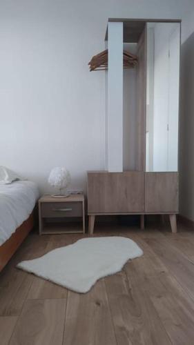 - une chambre avec un lit, un miroir et un tapis blanc dans l'établissement Charmant T1Bis rénové avec goût, à Rodez