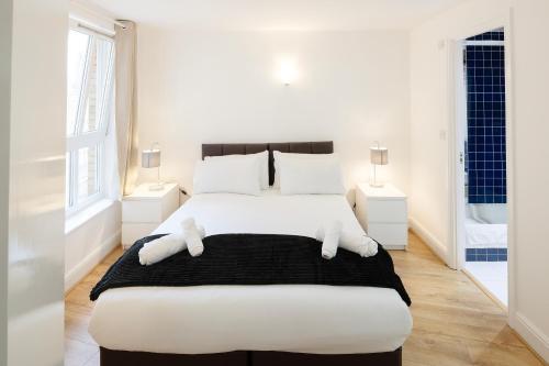 a white bedroom with a large bed with two teddy bears on it at Modern and spacious 2-BR, 2-BA retreat near Tower Bridge in London