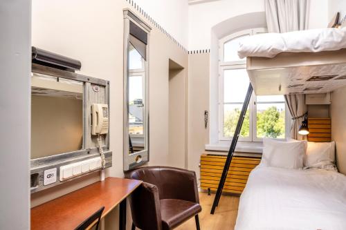 a bedroom with a bunk bed and a desk and a tv at STF Långholmen Hostel in Stockholm