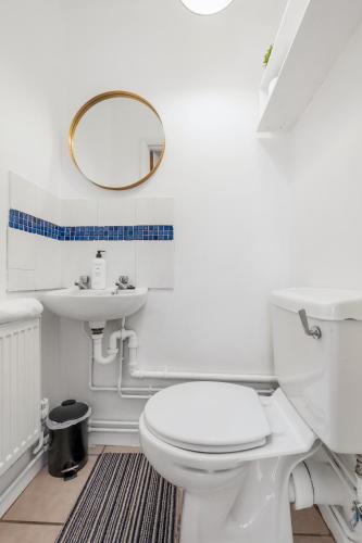 a bathroom with a white toilet and a mirror at 4 Bedroom House with Parking & Garden by Cherry Inn Short Let's & Services Accomodation in Cambridge