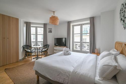 - une chambre avec un lit blanc, une table et des chaises dans l'établissement Paris, Opéra 4...So parisian Apartment, à Paris