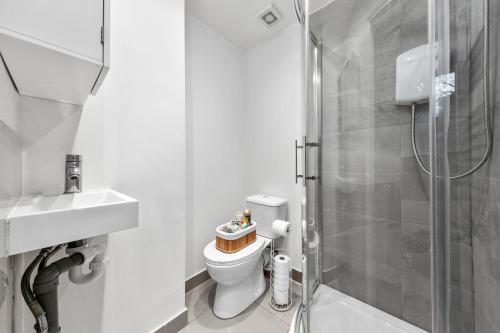 La salle de bains est pourvue de toilettes et d'une douche en verre. dans l'établissement Olympia Kensington Stay Studio, à Londres