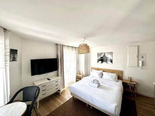 une chambre avec un lit blanc et une télévision dans l'établissement Paris, Opéra 5...Charming apartment in Paris, à Paris