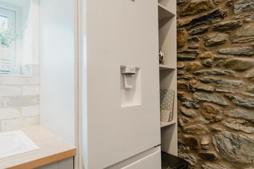 a glass refrigerator in a kitchen with a stone wall at The Cow Shed at Pencraig in Holyhead