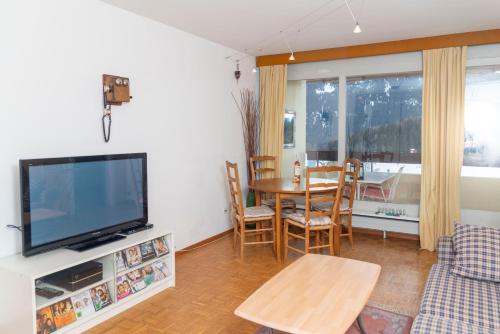 a living room with a tv and a table with chairs at Residence Clos Soleil 22a in Leysin