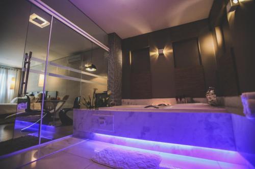 uma grande casa de banho com uma banheira com iluminação roxa em Gontijo Inn Hotel em Itajubá