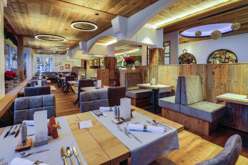 een restaurant met houten vloeren en tafels en stoelen bij Alpenhotel Fischer 4 Sterne - Adults Only in Berchtesgaden