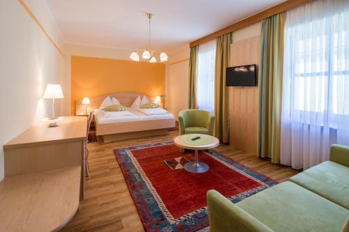 ドイチュランツベルクにあるGasthof-Restaurant Kollar Göblのベッドとリビングルームが備わるホテルルームです。